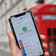 A person holds up a phone with the NHS contact tracing app active in front of a red phone booth.